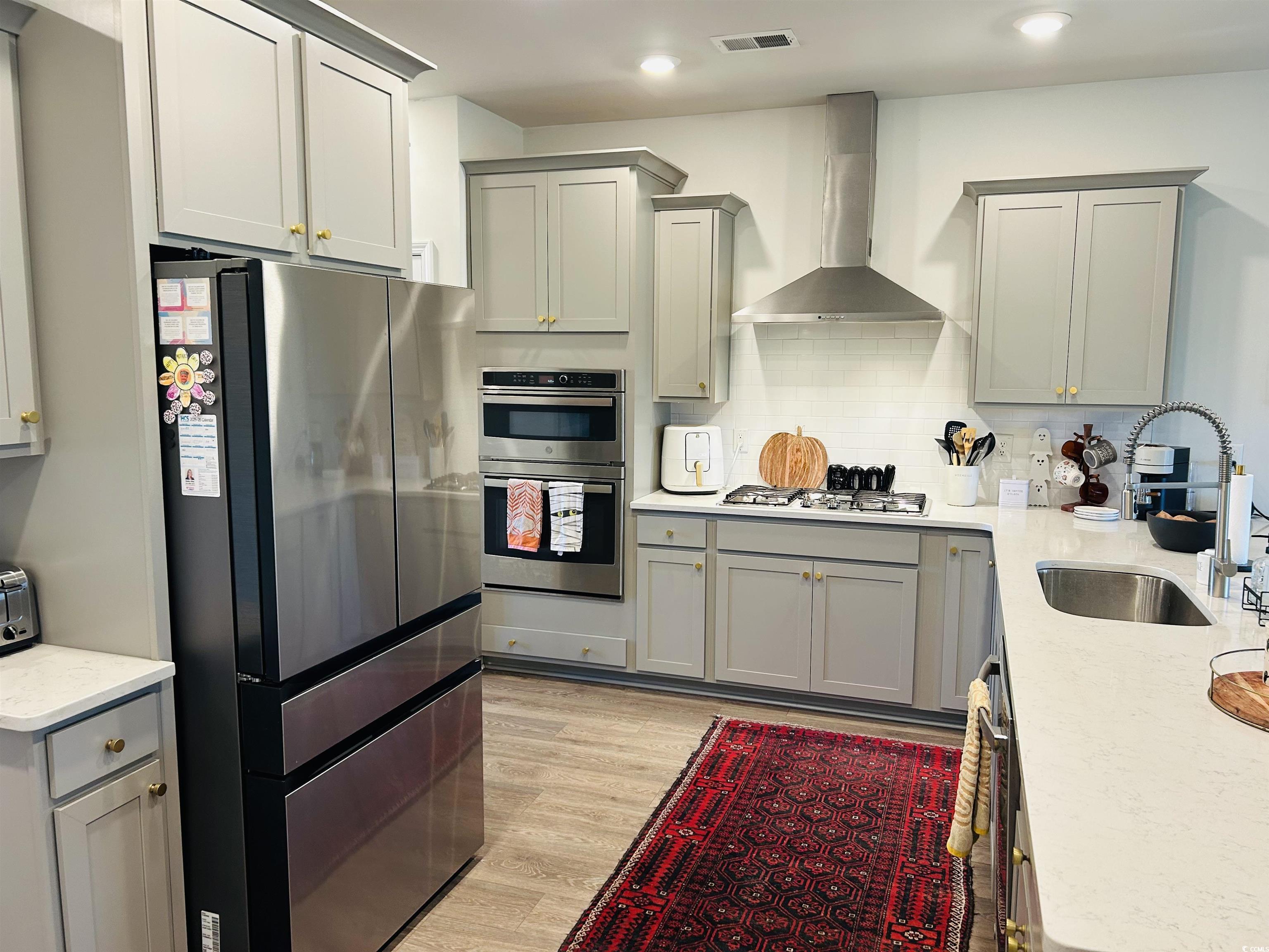 609 Shortleaf Path Myrtle Beach, SC 29577 - Photo 8 of 40 Kitchen featuring gray cabinetry, appliances with stainless steel finishes, light stone counters, light wood-style flooring, and recessed lighting
