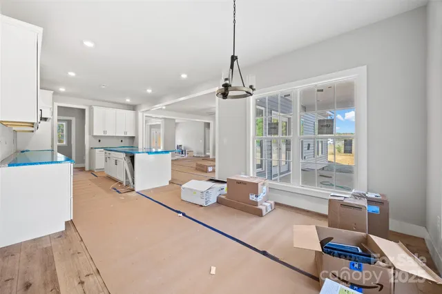 a kitchen with stainless steel appliances granite countertop a sink dishwasher and white cabinets with wooden floor