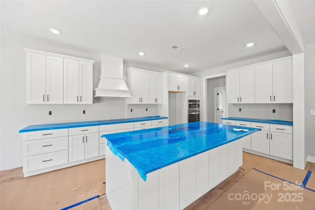 a hall with kitchen island a stove a wooden floor and a chandelier