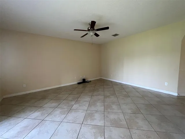 an empty room with a ceiling fan and carpet
