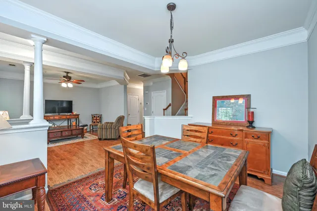 a dining room with wooden floor a chandelier a wooden table and chairs
