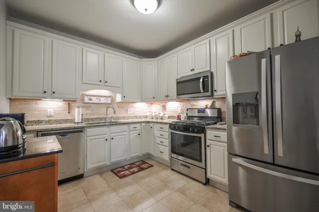 a kitchen with granite countertop a refrigerator stove top oven and sink