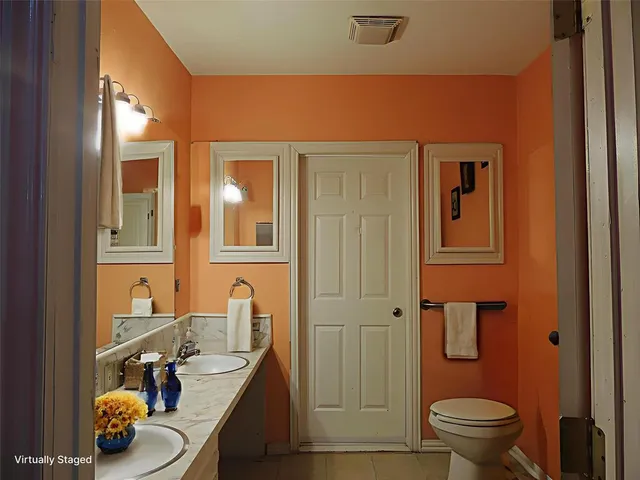 a bathroom with a granite countertop sink and a toilet