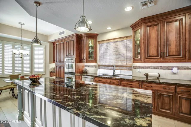 a kitchen with granite countertop a stove a sink a dining table and chairs