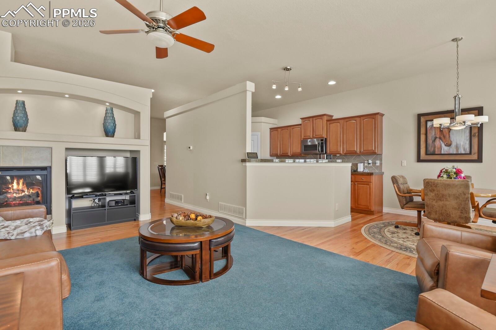 617 Concerto Drive Colorado Springs, CO 80906 - Photo 11 of 46 This inviting open plan living area features a fireplace with a tiled surround, nooks for tv and artwork displays, a ceiling fan, and hardwood flooring that extends into the adjacent dining area and kitchen