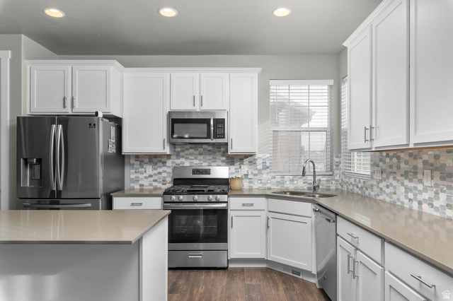 5686 Duke Lane Tooele, UT 84074 - Photo 25 of 38 Kitchen with stainless steel appliances, white cabinetry, dark wood-style flooring, recessed lighting, and light stone counters