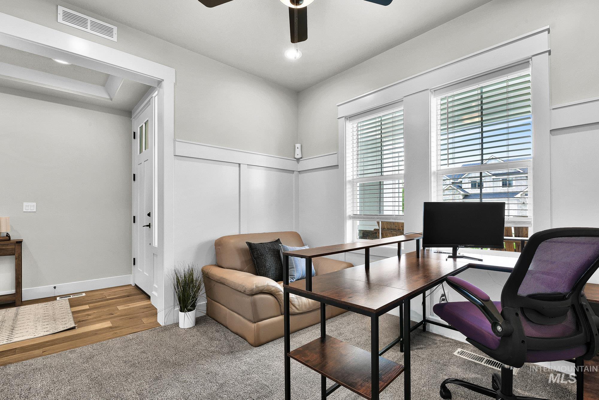 5676 East Zaffre Ridge Street Boise, ID 83716 - Photo 5 of 50 Carpeted interior space featuring white board and batten wall details, two double-hung windows with blinds, a ceiling fan, and wood-finish flooring at the entryway