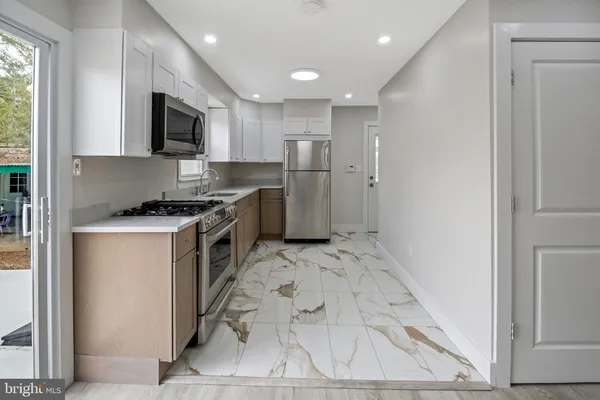 a view of kitchen with stainless steel appliances wooden floor and window