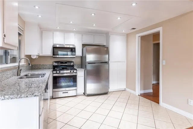 a kitchen with stainless steel appliances a refrigerator a stove a sink and a refrigerator