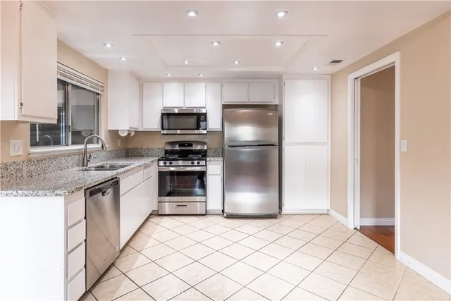 a kitchen with kitchen island granite countertop a refrigerator and a sink