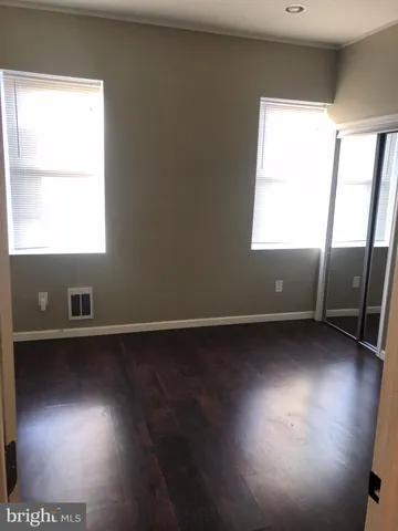 an empty room with wooden floor and windows with curtains