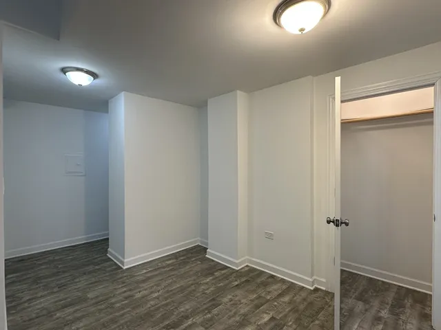 an empty room with chandelier fan and windows