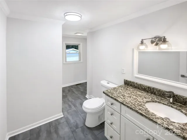 a bathroom with a granite countertop sink a toilet and a mirror