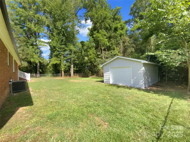 a backyard of a house with plants and large tree