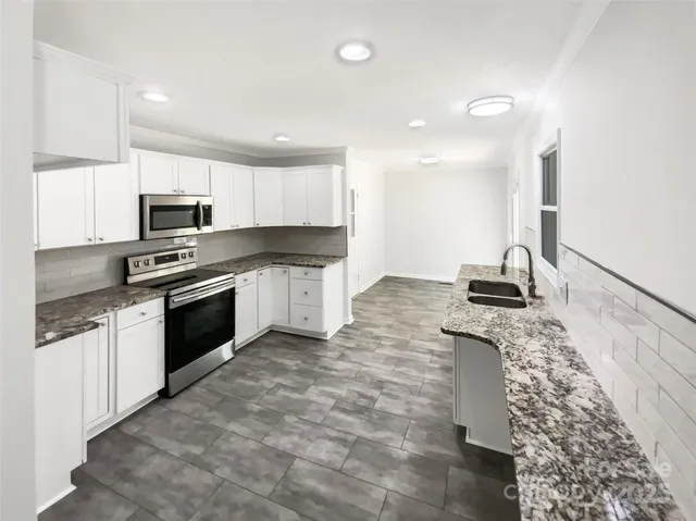 a kitchen with granite countertop a stove sink and microwave