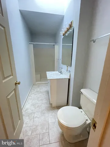 a white toilet sitting next to a bathroom sink and a mirror