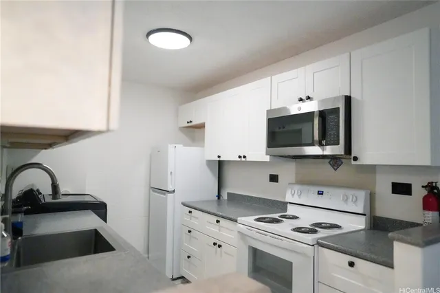 a kitchen with stainless steel appliances a white stove top oven and white cabinets