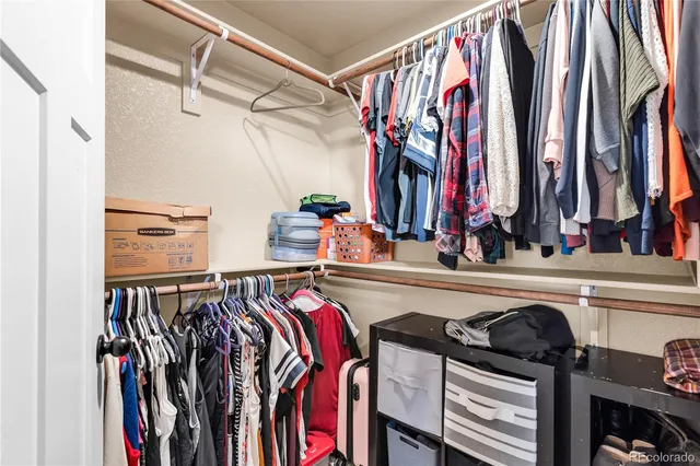a view of walk in closet with clothes and shoes