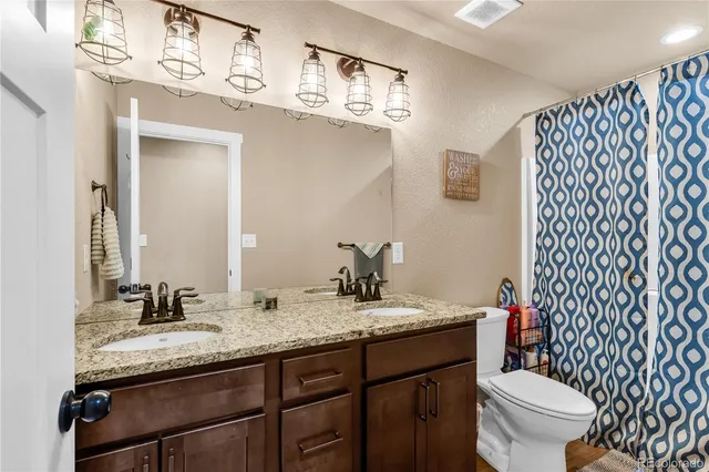 a bathroom with a granite countertop toilet sink and mirror