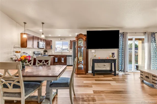 a living room with stainless steel appliances furniture a fireplace a flat screen tv and kitchen view