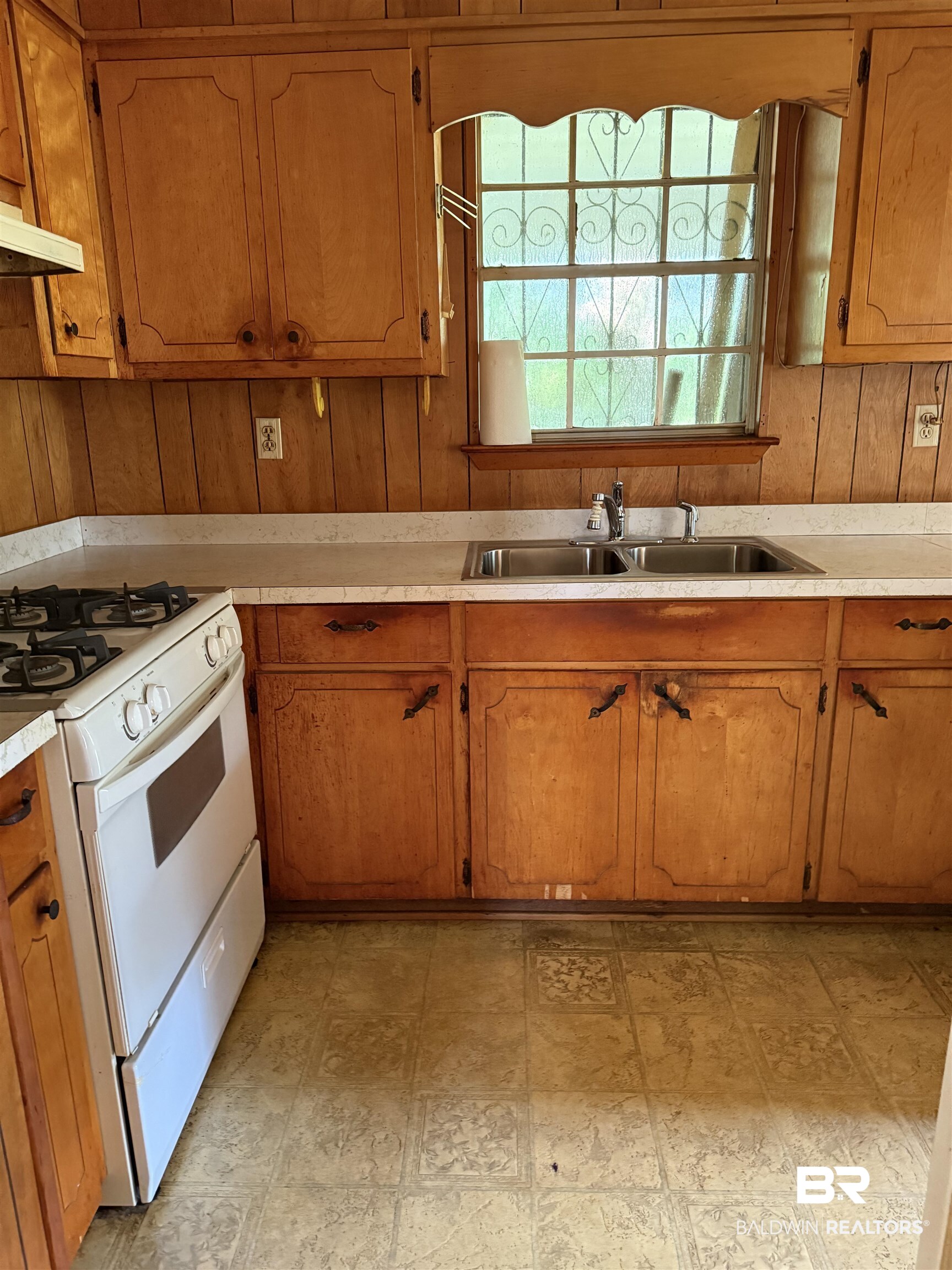 607 West Lee Street Mobile, AL 36611 - Photo 5 of 11 Kitchen with white gas range, light countertops, under cabinet range hood, brown cabinets, and wooden walls