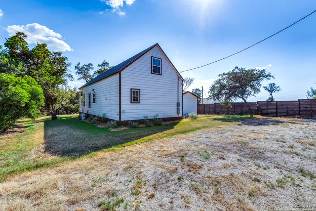 a view of backyard of house with wooden fence