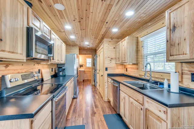 a kitchen with stainless steel appliances granite countertop a sink a stove and a wooden floors