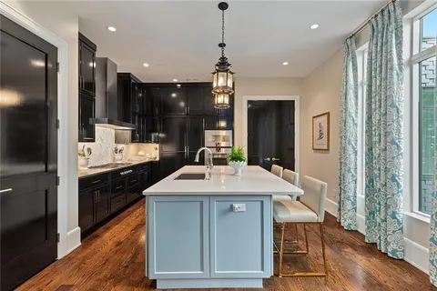 a large kitchen with sink a refrigerator and chairs