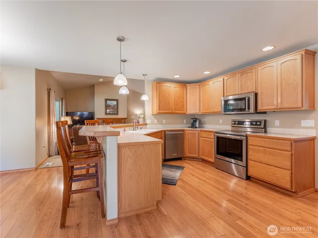 a kitchen with granite countertop wooden floors stainless steel appliances and a window