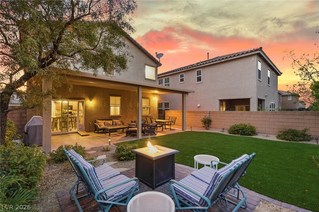 150 Fulgora Street Henderson, NV 89074 - Photo 12 of 92 Back of property at dusk featuring a patio, stucco siding, an outdoor living space with a fire pit, and a fenced backyard