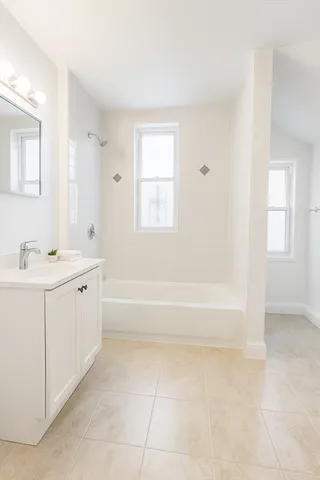 a spacious bathroom with a bathtub sink and mirror