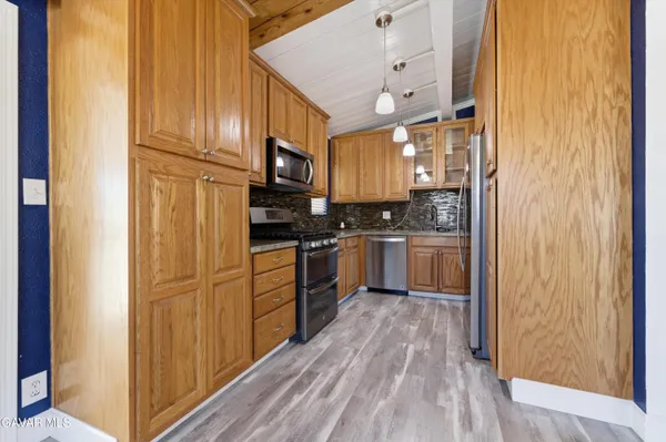 a kitchen with cabinets stainless steel appliances and wooden floor
