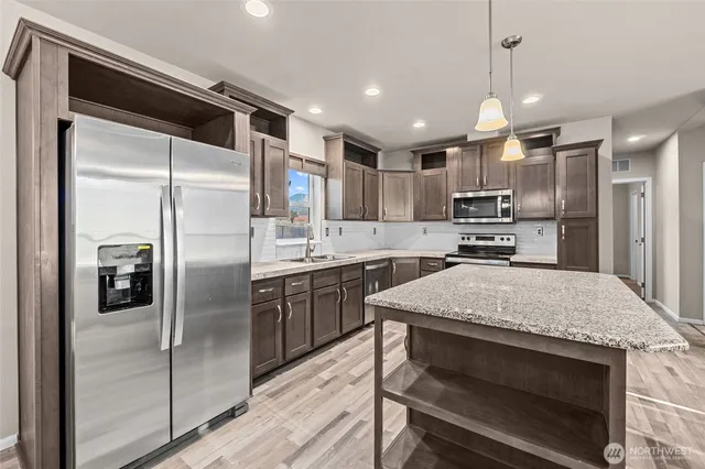 a kitchen with kitchen island a refrigerator stove microwave and cabinets