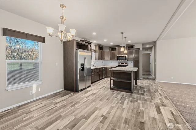 a kitchen with stainless steel appliances kitchen island granite countertop a refrigerator and a stove top oven