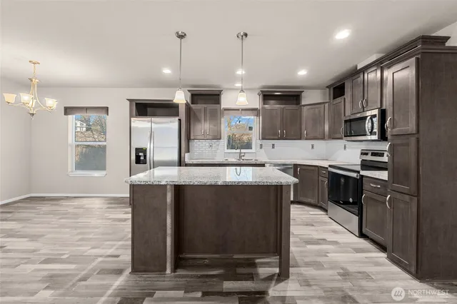 a kitchen with kitchen island a counter top stainless steel appliances and cabinets