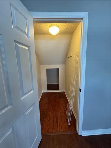 a view of hallway with window and wooden floor