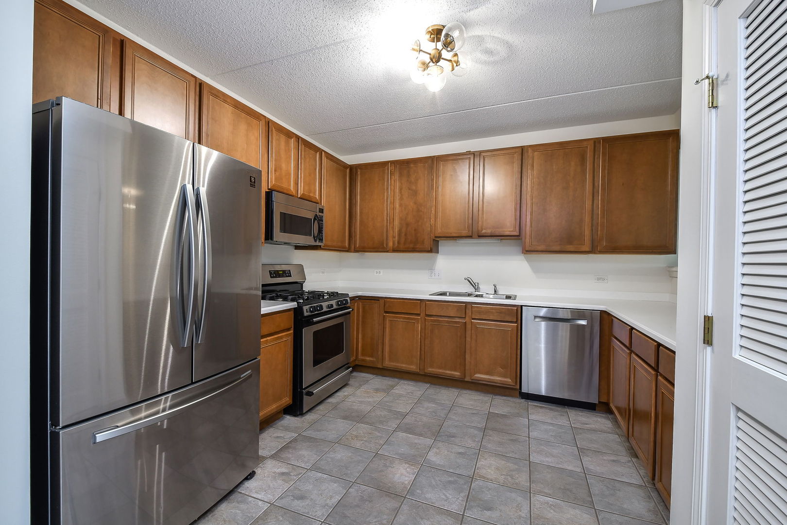 586 Crescent Boulevard, Unit 305 Glen Ellyn, IL 60137 - Photo 3 of 13 a kitchen with granite countertop stainless steel appliances and wooden cabinets