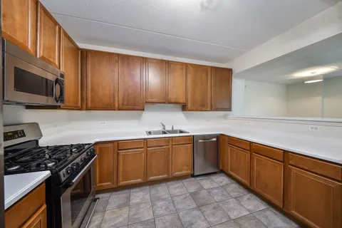 a kitchen with stainless steel appliances granite countertop wooden cabinets a stove top oven a sink and dishwasher