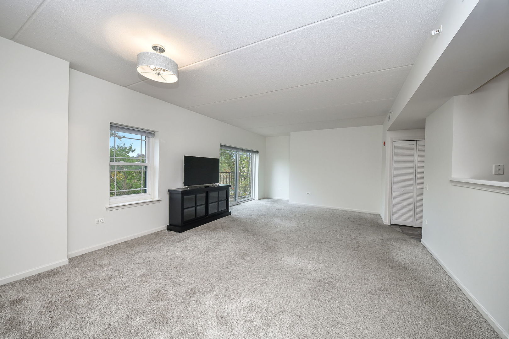 586 Crescent Boulevard, Unit 305 Glen Ellyn, IL 60137 - Photo 7 of 13 a view of a livingroom with furniture and a flat screen tv