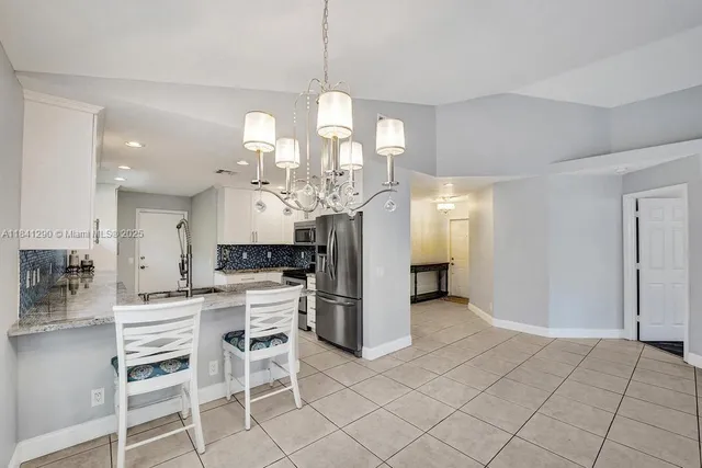 a kitchen with a dining table chairs cabinets and stainless steel appliances