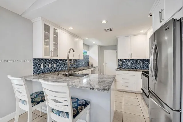 a kitchen with stainless steel appliances granite countertop a sink and a refrigerator