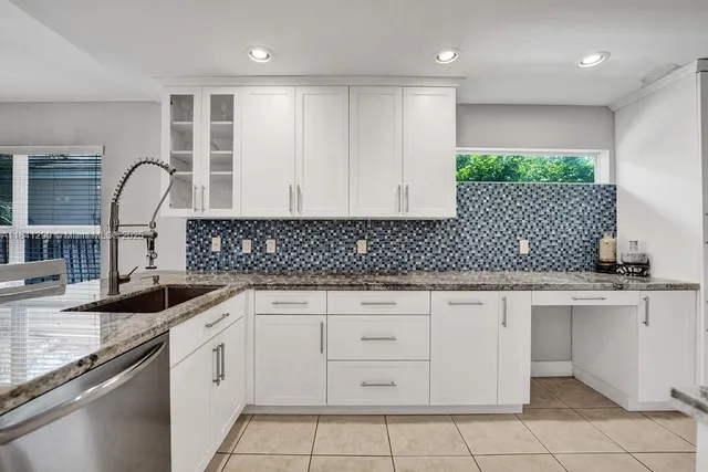 a kitchen with granite countertop white cabinets and sink
