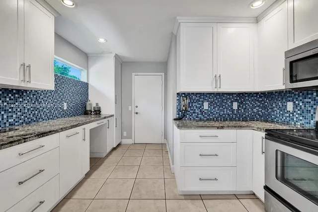 a kitchen with granite countertop white cabinets and stainless steel appliances