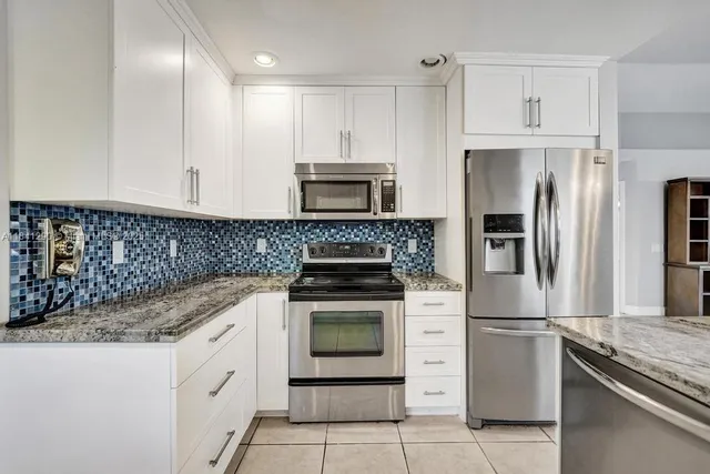 a kitchen with granite countertop white cabinets and stainless steel appliances