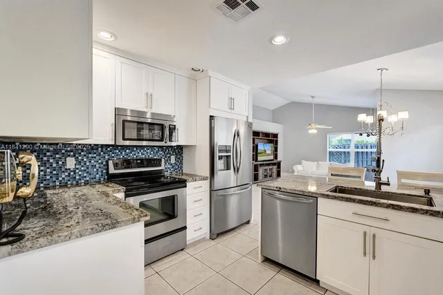 a kitchen with stainless steel appliances granite countertop a sink and a refrigerator