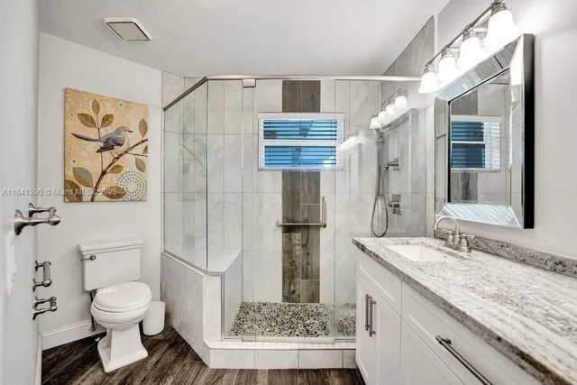 a bathroom with a granite countertop sink toilet and shower
