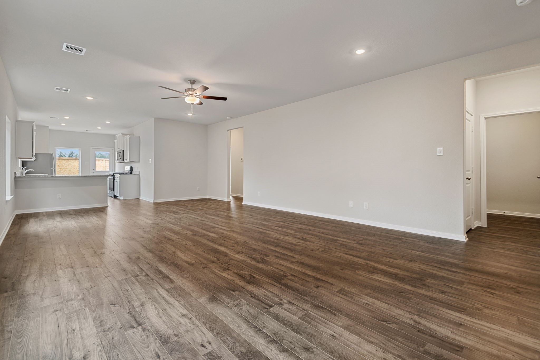 15434 Maple Ter Drive Conroe, TX 77303 - Photo 3 of 25 a view of an empty room with wooden floor and a kitchen