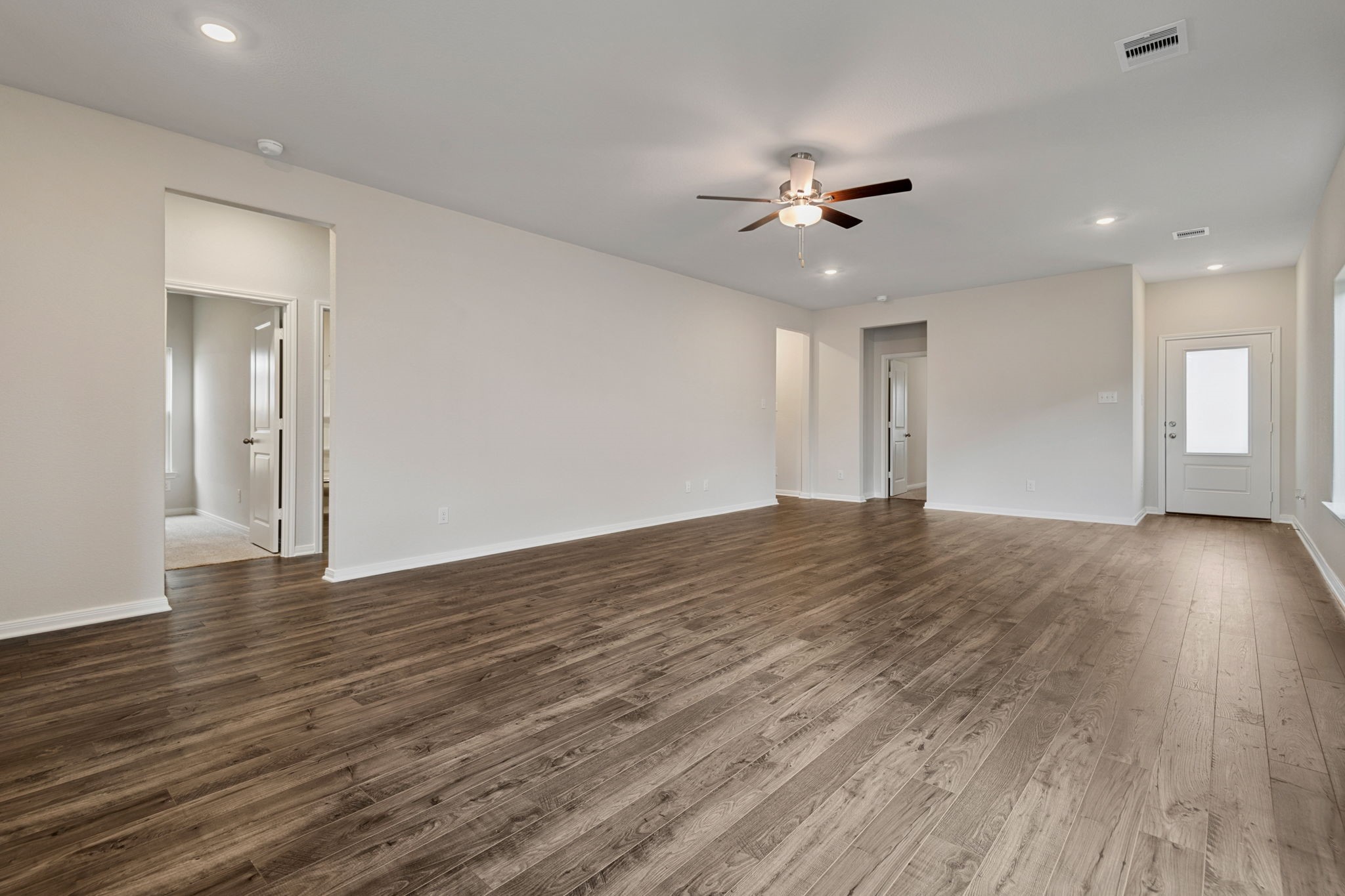 15434 Maple Ter Drive Conroe, TX 77303 - Photo 4 of 25 a view of an empty room with wooden floor and a ceiling fan