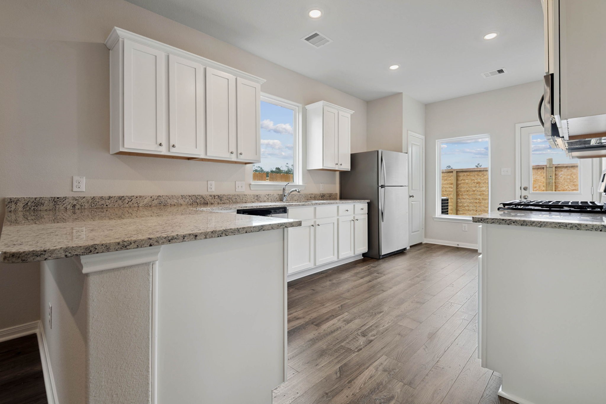 15434 Maple Ter Drive Conroe, TX 77303 - Photo 5 of 25 a kitchen with stainless steel appliances granite countertop a stove a refrigerator a sink and white cabinets with wooden floor