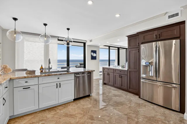 a kitchen with granite countertop a refrigerator and a stove top oven